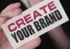 Unraveling The Mysteries of Personal Branding: 8 Most Asked Questions man holding up a create your brand sign - unlocking the mysteries of personal branding