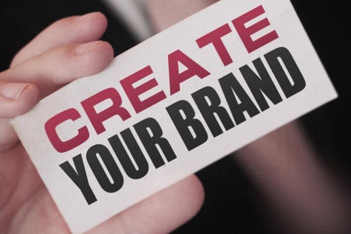 man holding up a create your brand sign - unlocking the mysteries of personal branding