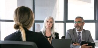 Crafting a CV for New Zealand’s Job Market: Tips and Tricks two people conducting an interview with a candidate while crafting a CV.