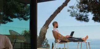 Navigating the Future of Remote Work: Embracing Trends & Technologies the future of remote work with a man sitting outside with his laptop overlooking the ocean
