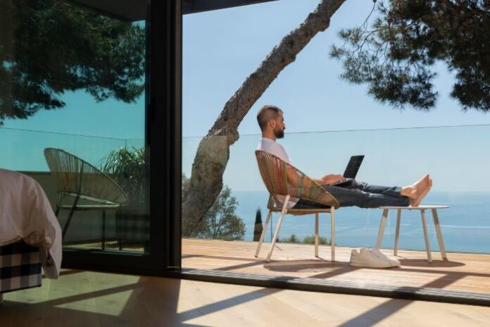 the future of remote work with a man sitting outside with his laptop overlooking the ocean