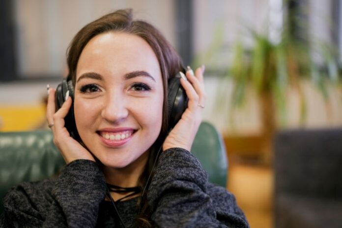 smiling girl holding her headset to her ears during call recording