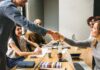 How to Enable Greater Collaboration in Your Business co-worker shaking hands in a meeting for better collaboration