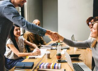 How to Enable Greater Collaboration in Your Business co-worker shaking hands in a meeting for better collaboration