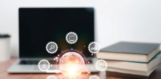 Exploring the Different Types of Knowledge Management Systems digital icons overlaid on a desk with books and laptop signifying knowledge management systems