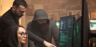 What Businesses are Vulnerable to DDoS Attacks? Three hackers around a monitor performing Ddos attacks.