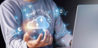 How to Reduce Churn Among Enterprise SaaS Customers Man reducing churn at desk using laptop and holding a graphic cloud.