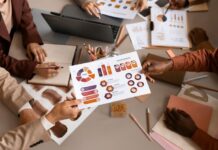 9 Steps Towards an Improved Marketing Plan A team working around a table with charts making a marketing plan