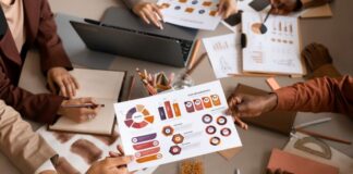 9 Steps Towards an Improved Marketing Plan A team working around a table with charts making a marketing plan