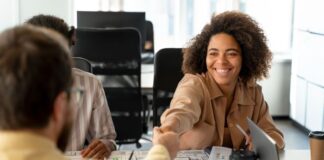 4 Key Areas You Should Outsource In Your Business Professional woman at desk shaking hands with colleague, while they outsource in her business.