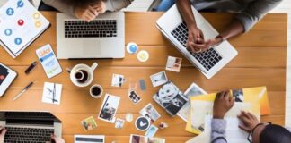 How To Elevate Your Marketing Game As A Business 4 workers around a table with papers and coffee, working on a marketing game