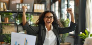 Make Your Business More Efficient and See More Business Success A woman is sitting at a desk with her hands up in the air celebrating business success and the word graph on the top of the desk