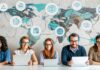 The Synergy of Mobile Technology and Top-Up in Global Communication five people on laptops with a world map behind them, engaging in global communication