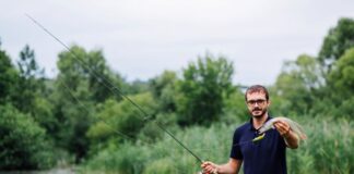 Fishing Apps Transforming Skills of Modern Anglers with New Technology Modern angler in a stream holding a rod and fish