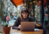 How Tech is Making Online Business Degrees More Accessible & Affordable Woman looking at business degrees online at a cafe