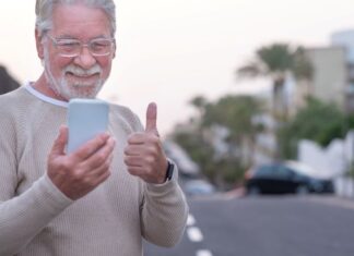 Empowering Seniors: 7 Benefits of GPS Technology GPS device empowering seniors to be independent, shown with elderly man outside giving thumbs up at his phone
