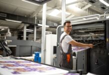 How Your Business Can Improve Sustainability Through Green Printing smiling man doing green printing on industrial printer