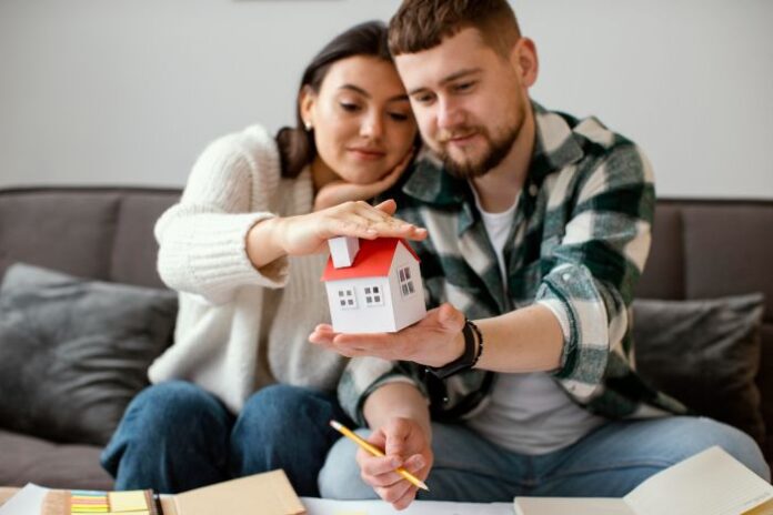 couple that made their first home purchase, holding a toy house