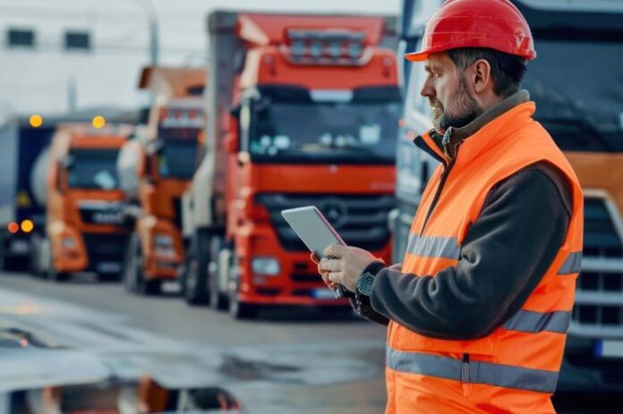 cut fleet costs with AI, shown with manager using tablet in front of fleet