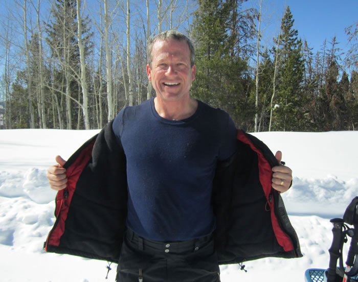 Charles Lambert smiling with his coat open on the ski slope