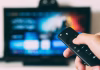 How Smart TV Technology Is Changing Commercial DIRECTV Installations a person holding remote