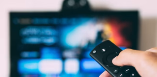 How Smart TV Technology Is Changing Commercial DIRECTV Installations a person holding remote