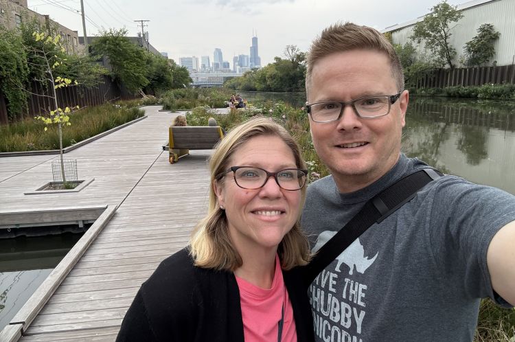 Christopher Sprague smiling with his wife and the Chicago skyline in the background.