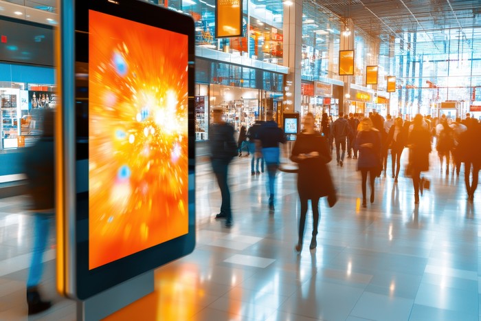 people in a mall walking by digital signage
